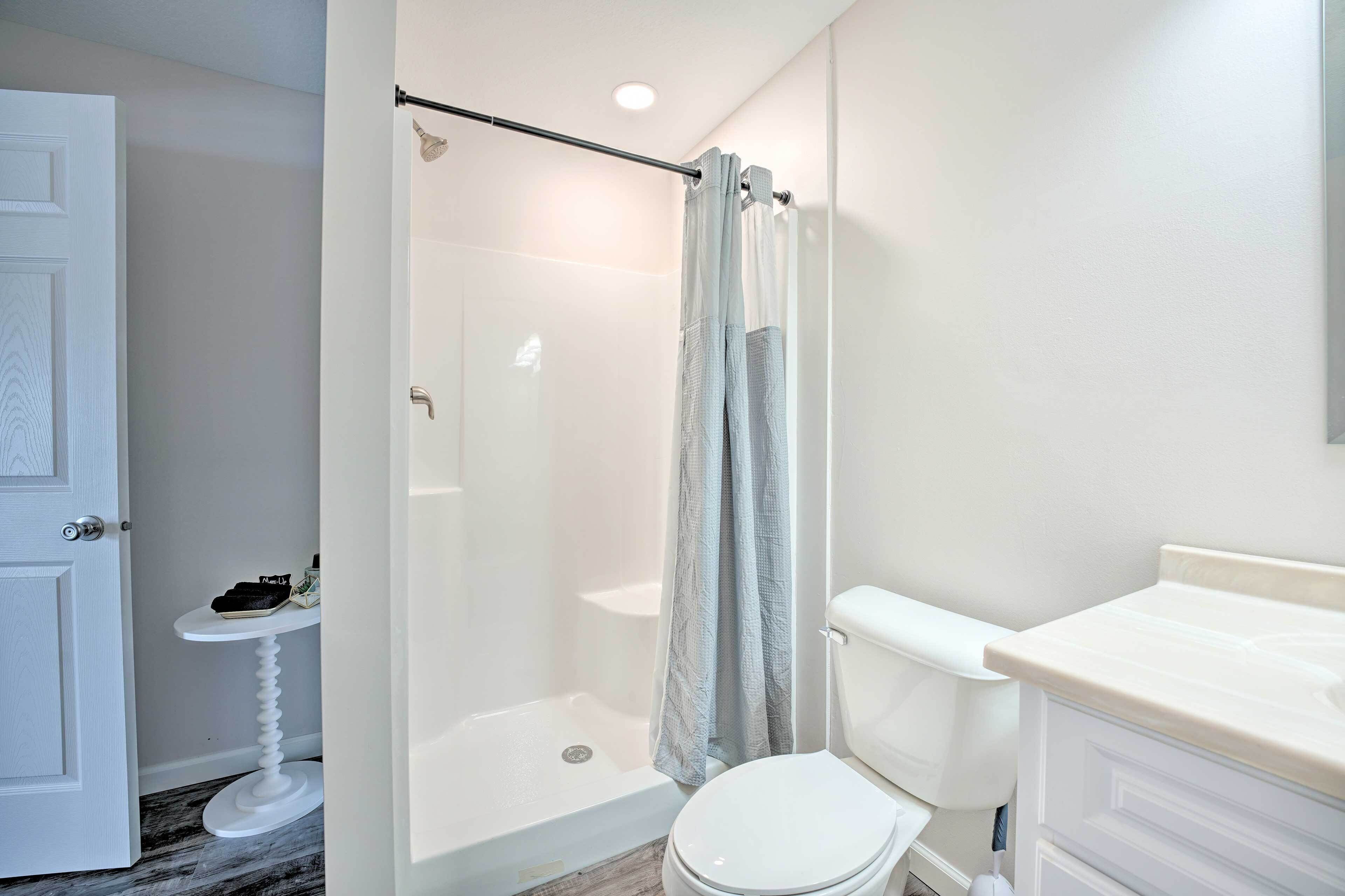 Une salle de bain avec douche, toilettes et lavabo.
