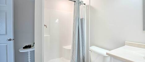 Une salle de bain avec douche, toilettes et lavabo.