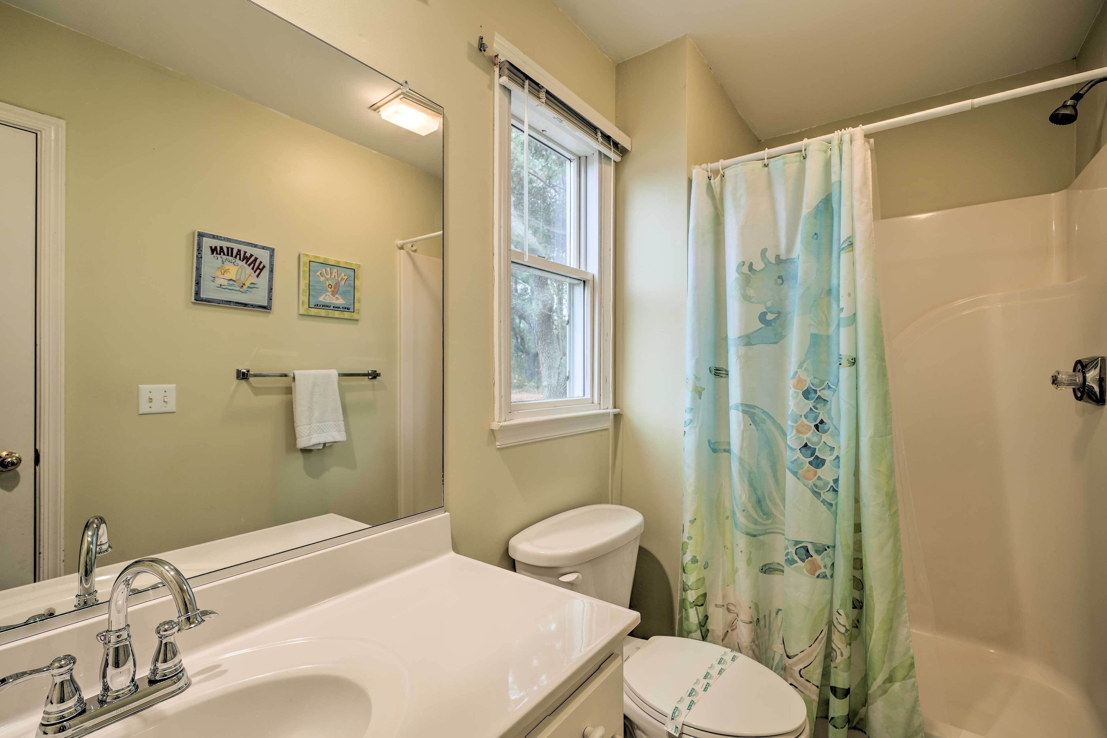 Un baño con un espejo grande, una bañera, un inodoro y un lavabo.