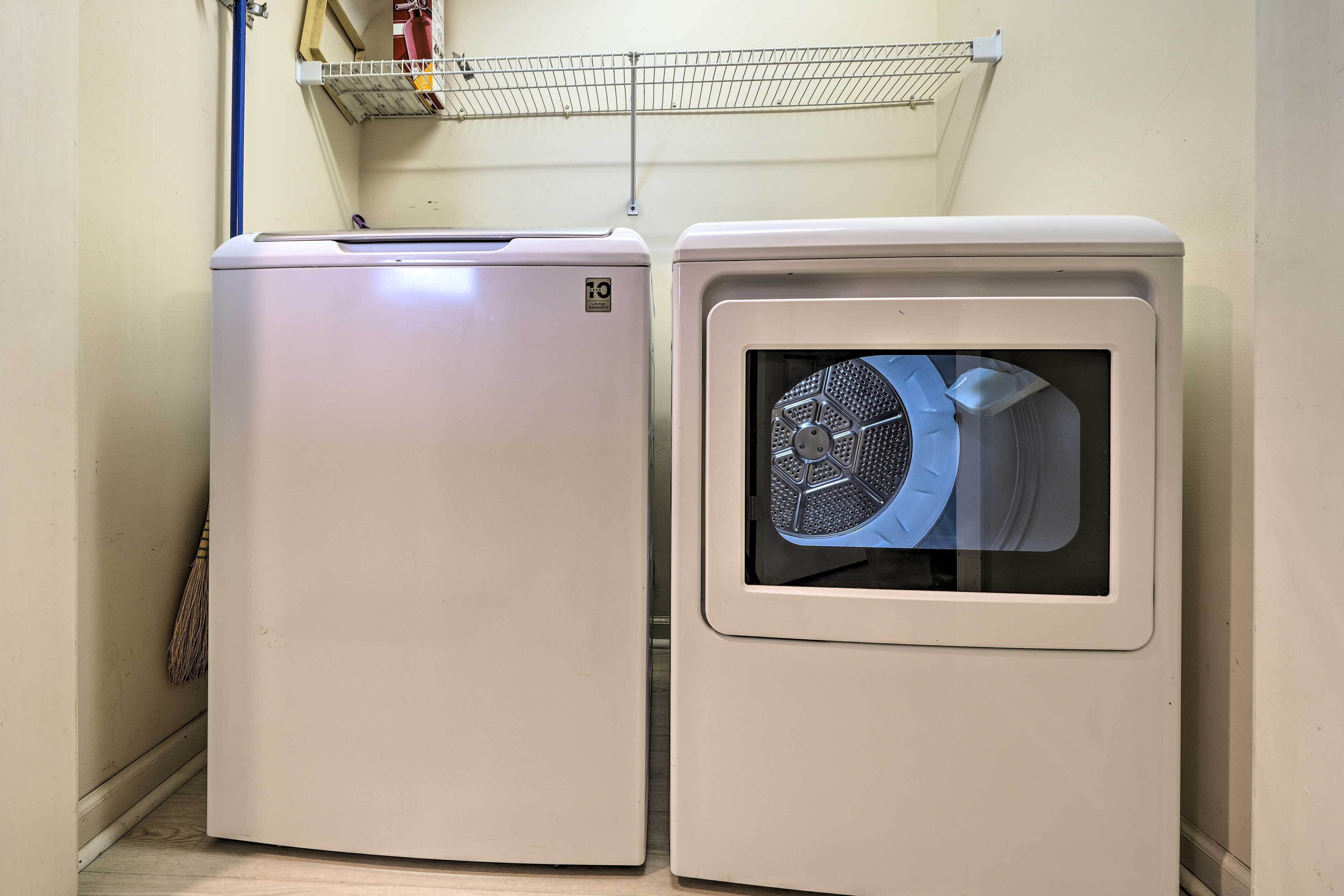 Twee witte apparaten, waarschijnlijk een wasmachine en droger, staan in een hoek met een metalen plank erboven.