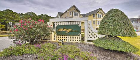 A hotel with a well-maintained garden, a signboard, and a neatly trimmed tree.
