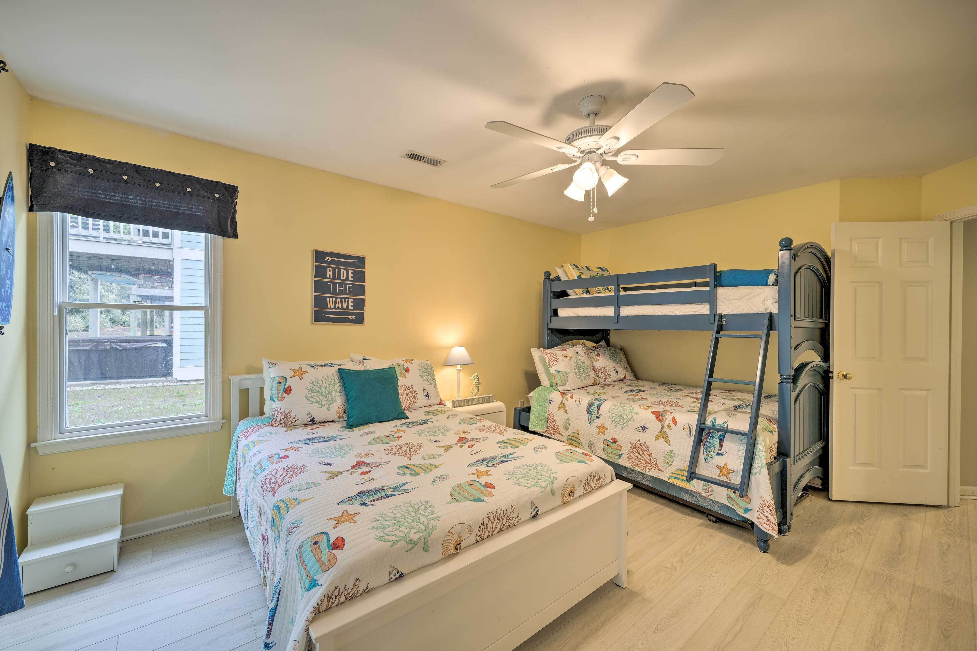 A bedroom with two bunk beds, a ceiling fan, a window with a view, and a door.