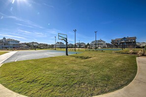 A basketball court with a net, surrounded by grass and a few benches. - Coastal Home w/ Community Pool < 2 Miles to Beach! (Corolla)