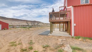 Un bâtiment rouge doté d’un balcon, avec un chemin de terre au premier plan.