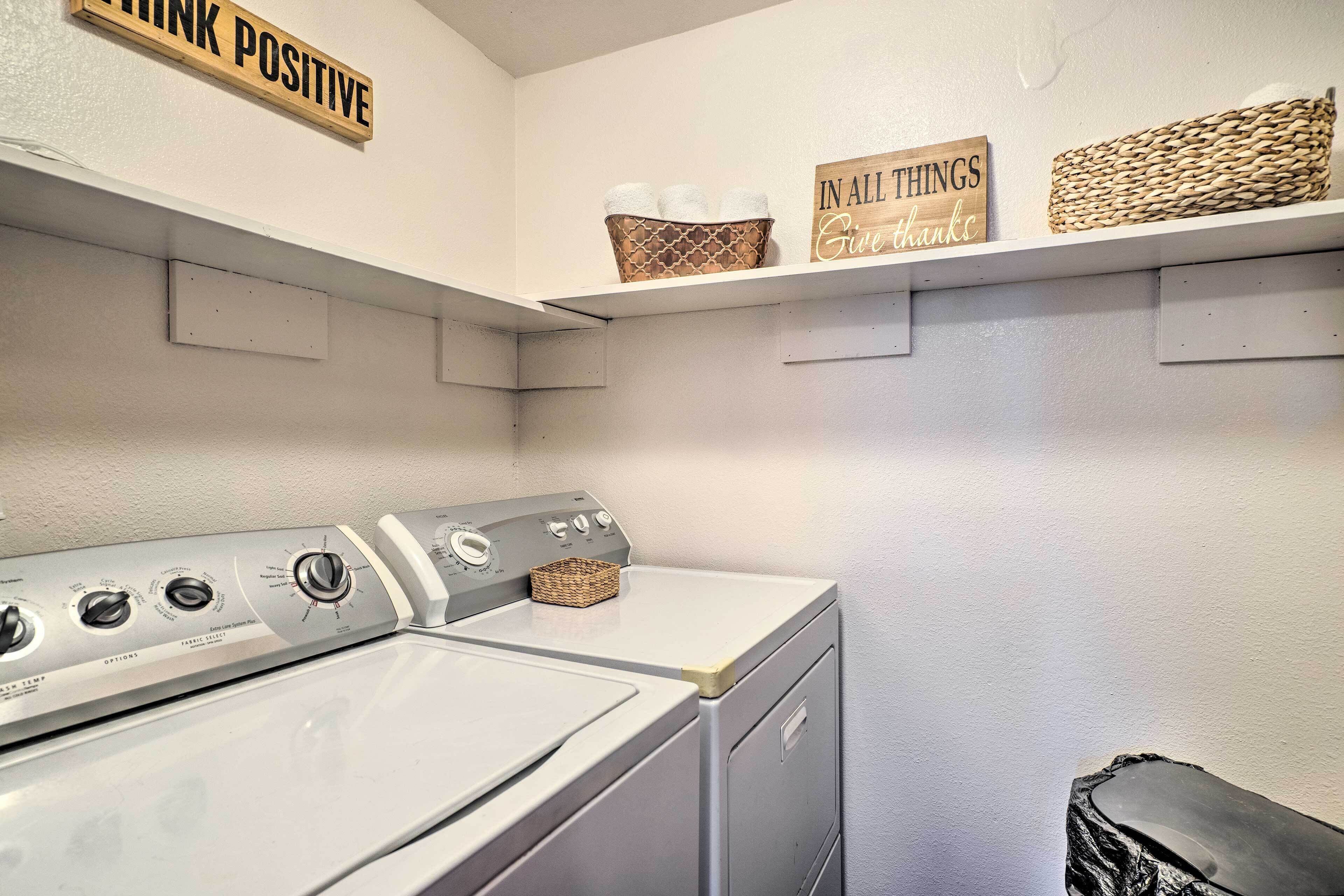 A laundry area with a washer and dryer, shelves with baskets and signs, and a wall-mounted shelf with baskets.