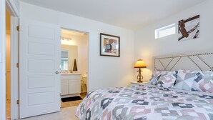 A bedroom with a bed, a bedside lamp, a headboard, and a door leading to a bathroom. - Colorado Retreat Near Hiking, Golfing & Fishing! (Commerce City)