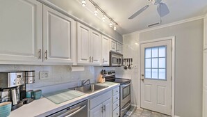 Una cocina con armarios blancos, electrodomésticos de acero inoxidable y un salpicadero de azulejos.