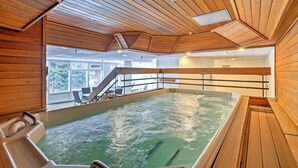 Un interior de madera con un jacuzzi, techo de madera y vistas al exterior.