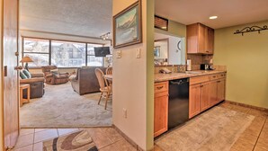 Un salón espacioso con un ventanal grande, una cocina con armarios de madera y una zona de comedor.