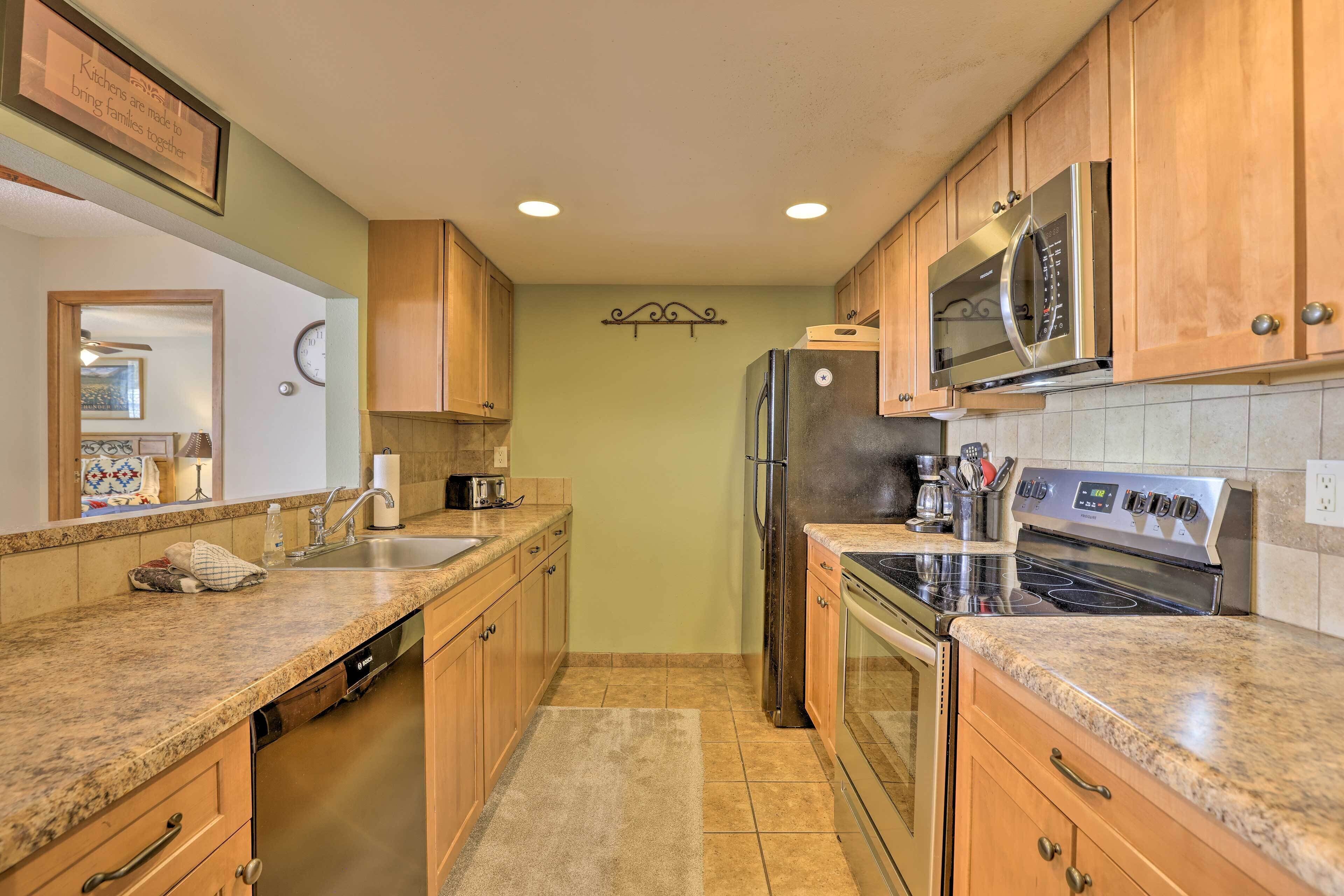 A kitchen with wooden cabinets, a stainless steel refrigerator, a microwave, and an oven.