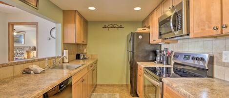A kitchen with wooden cabinets, a stainless steel refrigerator, a microwave, and an oven.
