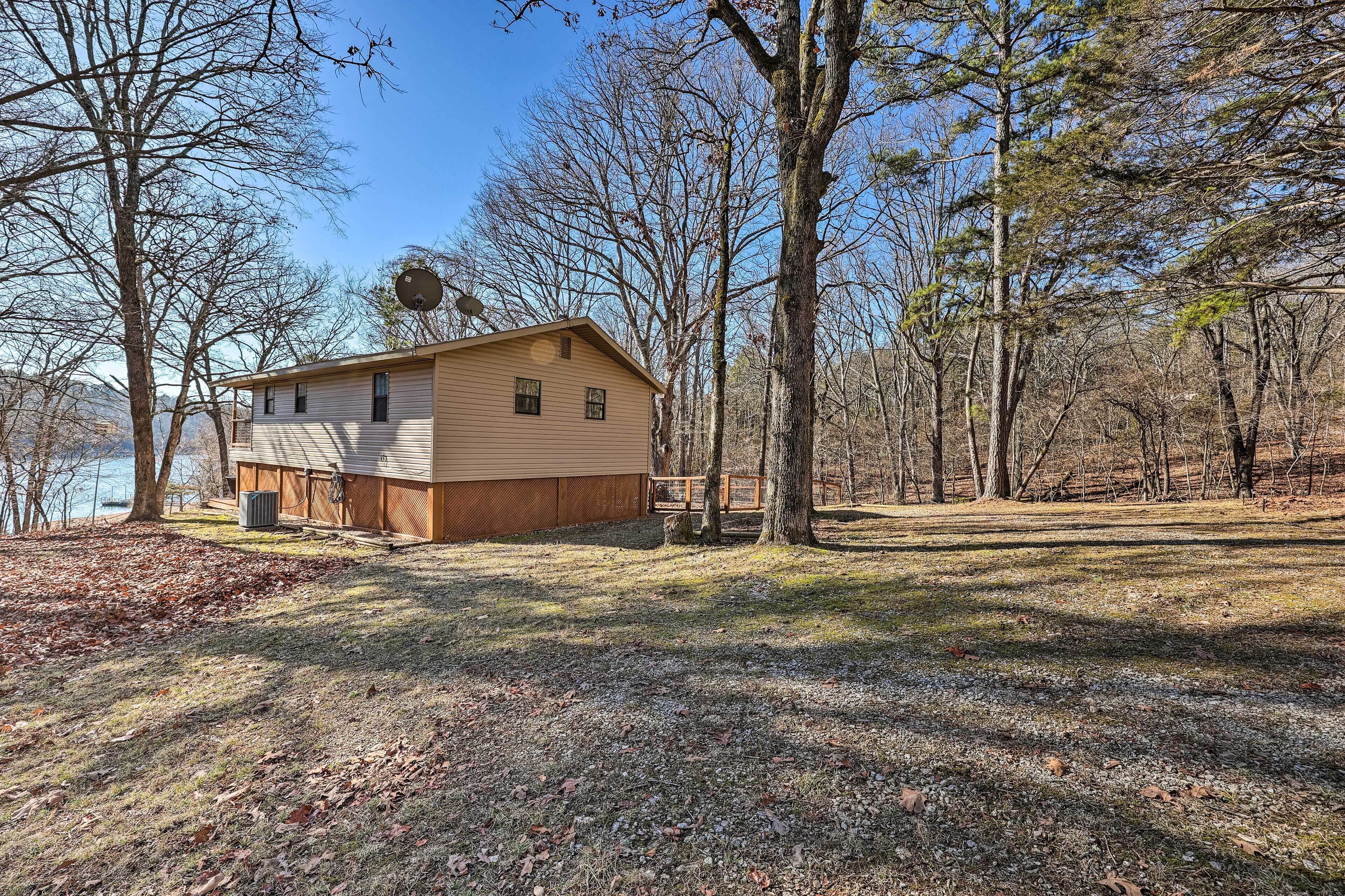 A single-story cabin with a sloped roof, surrounded by trees and a clear sky.