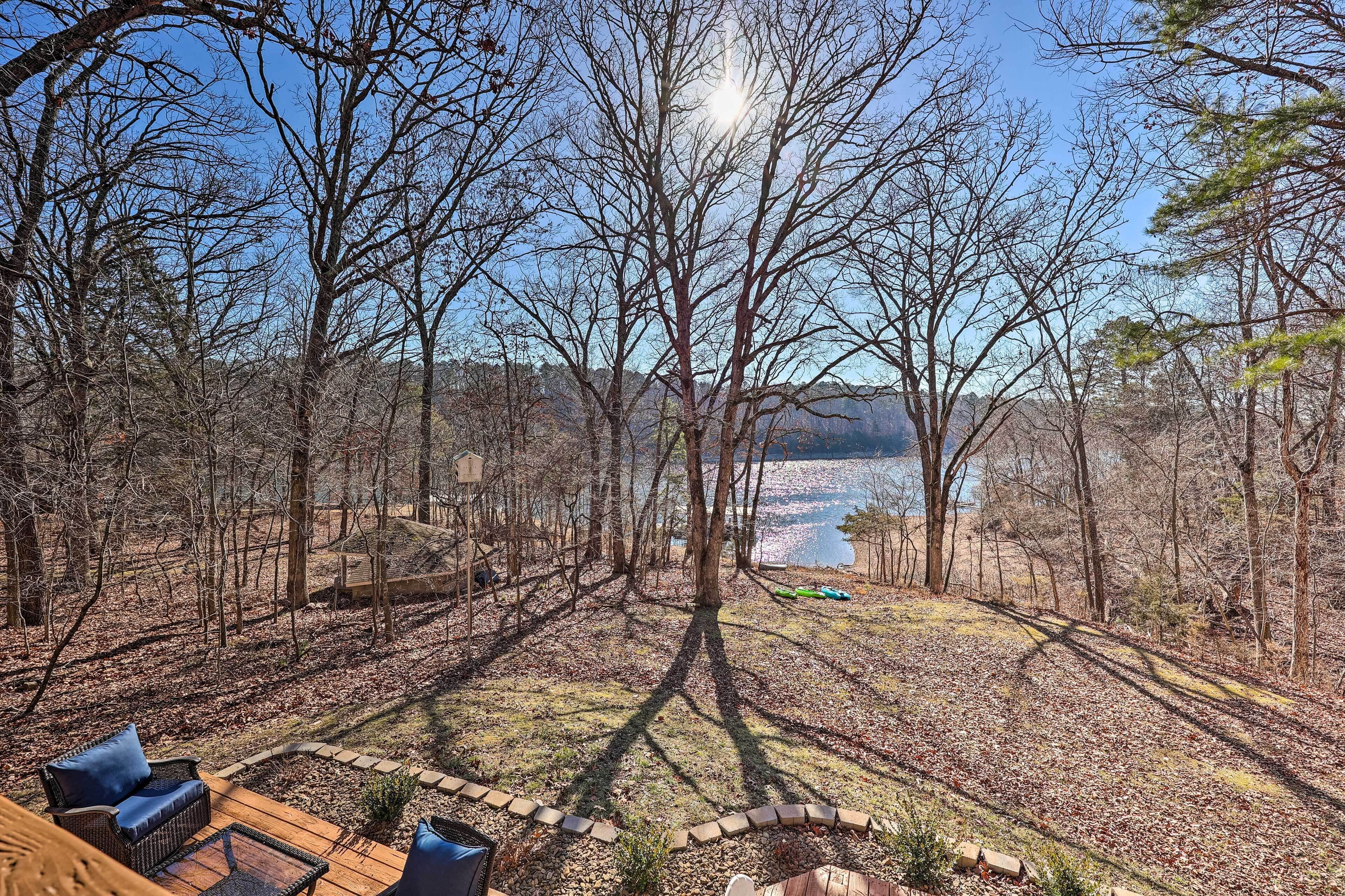 Une terrasse avec des sièges extérieurs donnant sur un lac, entourée d’arbres.