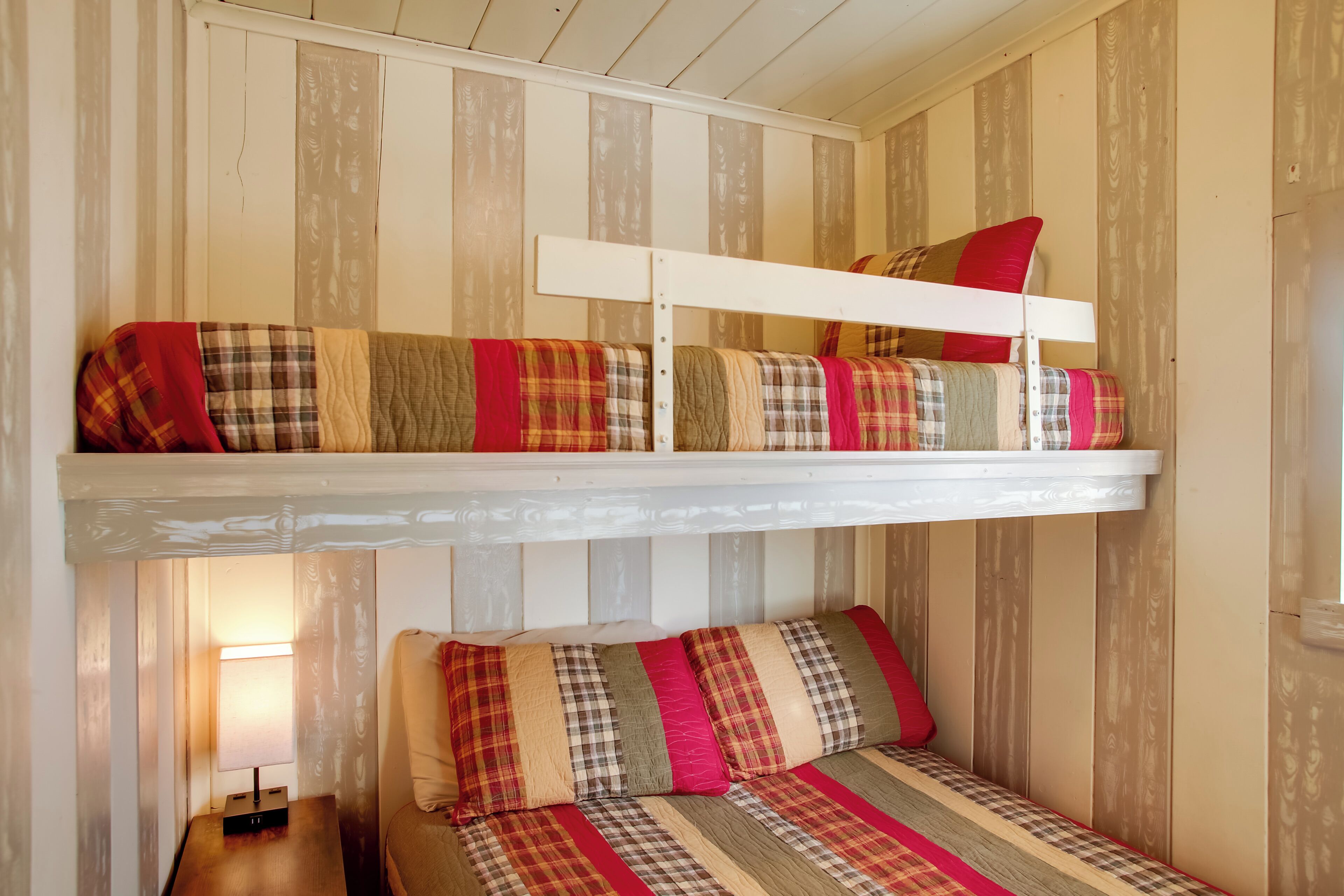 Uma beliche com roupa de cama listrada e uma cama simples com roupa de cama semelhante.