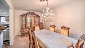 Une salle à manger avec une grande table en bois, des chaises décorées, un lustre et un buffet en bois.