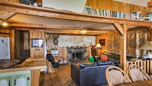 Interior d'una cabana acollidora amb una llar de foc, mobles de fusta i una prestatgeria.