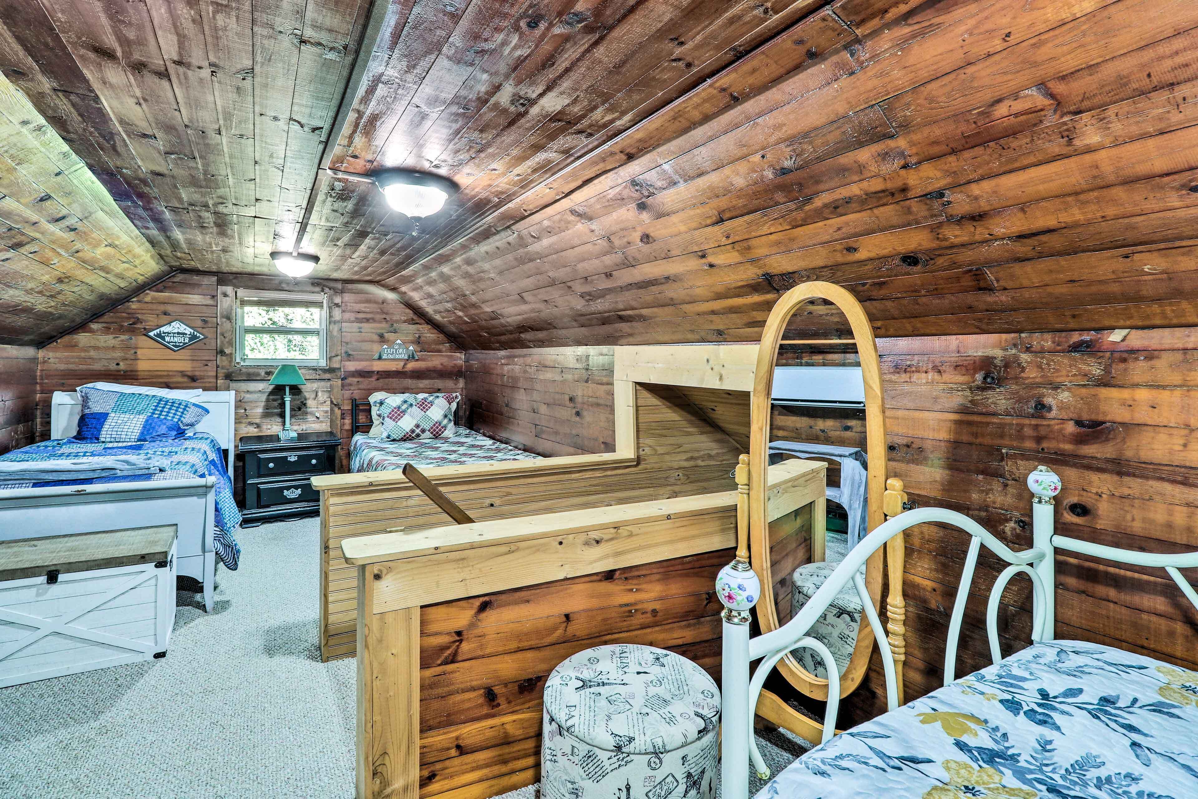 Une chambre confortable située sous les toits, avec des murs en bois, un plafond en pente et un lit recouvert d’une couette à carreaux bleus et blancs.