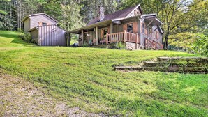 A cabin with a porch and a small shed, surrounded by a grassy area and trees. - Rustic Cabin w/ Patio & Pond on Blue Ridge Parkway (Ennice)