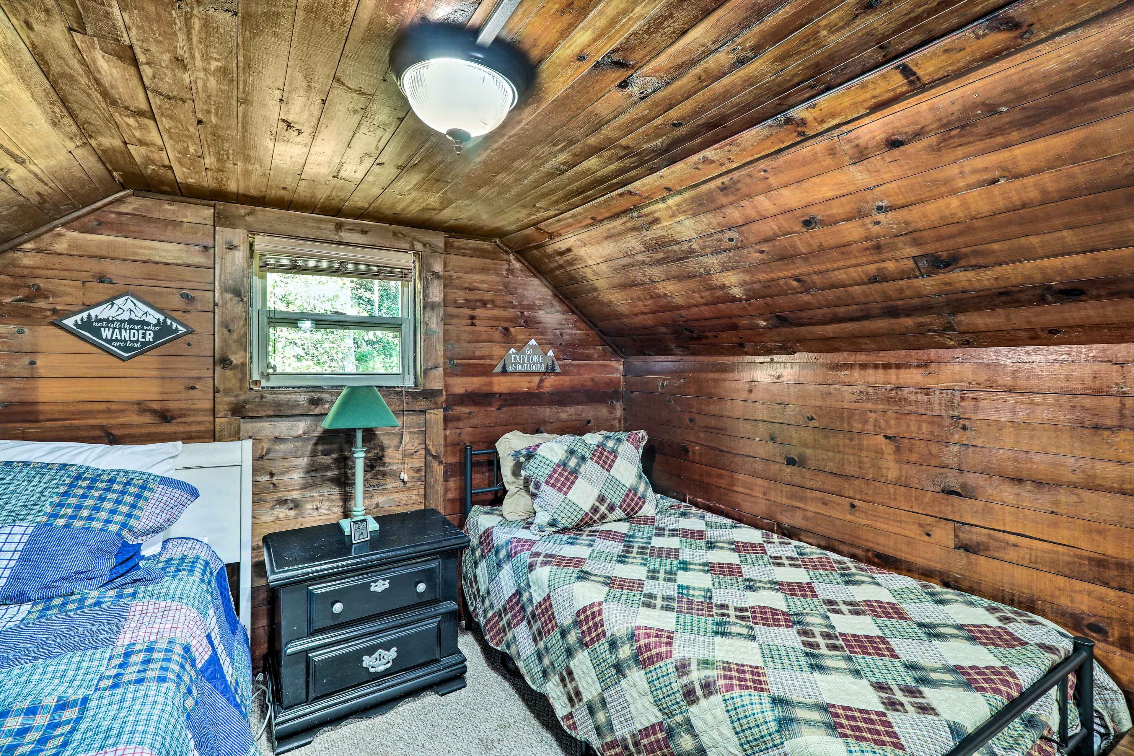 A cozy wooden cabin room with a bed, a dresser, and a window.
