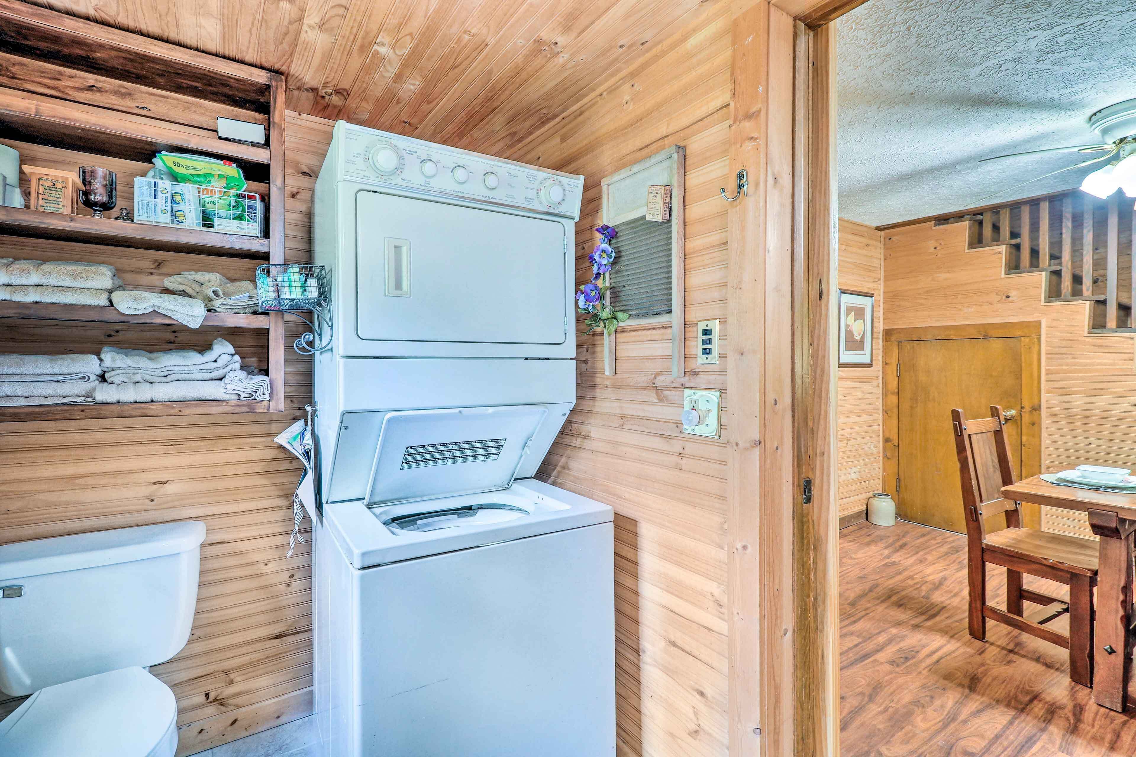 A compact wooden cabin with a washing machine, a toilet, and a dining area with a table and chair.