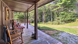 A wooden deck with a covered area, a rocking chair, and a bench. - Rustic Cabin w/ Patio & Pond on Blue Ridge Parkway (Ennice)