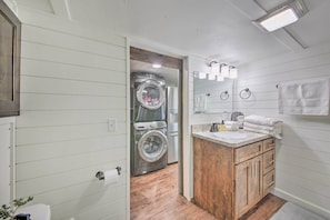 A compact bathroom with a wooden vanity, a washing machine, and a toilet.