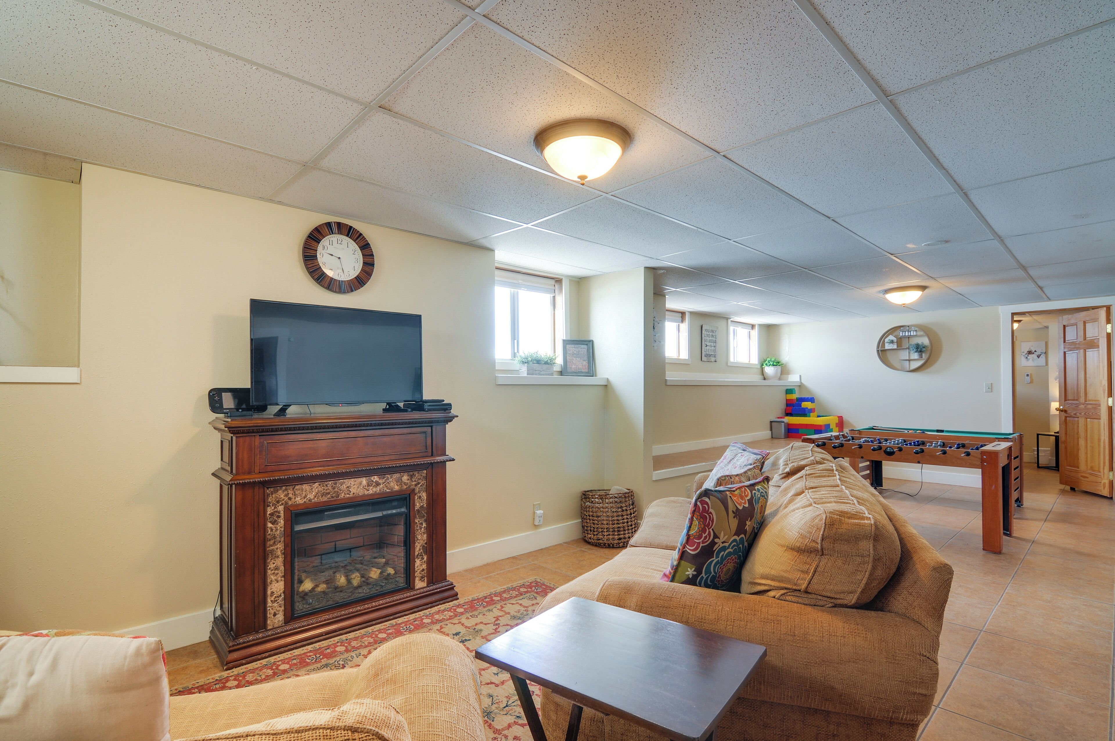 A living room with a fireplace, a television, a sofa, and a foosball table.