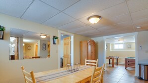 A dining area with a wooden table and chairs, a mirror, and a ceiling light fixture. - Cozy Historic Home w/ Games, Near Bryce Canyon! (Cannonville)