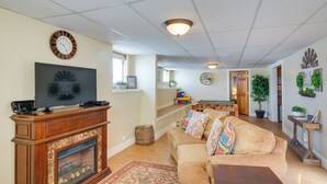 A living room with a fireplace, television, sofa, and a dining area with a table and chairs. - Cozy Historic Home w/ Games, Near Bryce Canyon! (Cannonville)