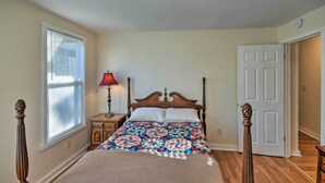 Un dormitorio con cama, mesita de noche, lámpara y puerta.