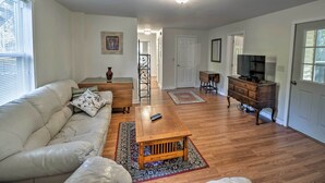 Un salón amplio con un sofá de cuero blanco, una mesa de centro de madera y un mueble para televisor.
