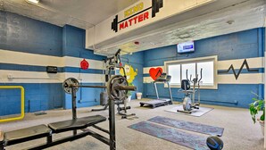 A gym with blue and white walls, a weight bench, a squat rack, and various exercise equipment.
