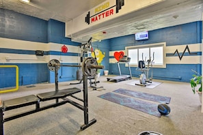Ett gym med blå väggar, en bänk för styrketräning, ett knäböjsställ och diverse träningsredskap.