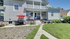 A two-story house with a front porch, a dining area with outdoor furniture, and a garden. - Eclectic Manitowoc Vacation Rental Near Marina! (Manitowoc)