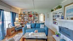 A living room with a sofa, coffee table, bookshelves, and a fireplace. - Eclectic Manitowoc Vacation Rental Near Marina! (Manitowoc)