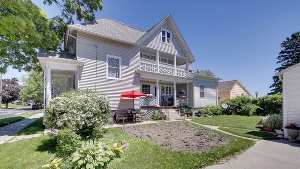 A two-story house with a front porch, a small garden, and a driveway. - Eclectic Manitowoc Vacation Rental Near Marina! (Manitowoc)