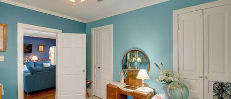 A bedroom with a bed, a dresser, a vanity with a mirror, a globe, and a chair.