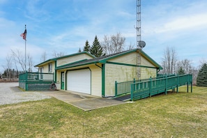 A single-story building with a garage, a small porch, and a satellite dish. - Cozy Cass City Retreat w/ Spacious Deck! (Cass City)