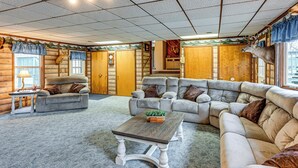A log cabin interior with a large sectional sofa, a wooden coffee table, and a fireplace. - Cozy Cass City Retreat w/ Spacious Deck! (Cass City)