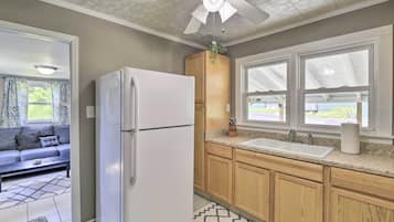 A kitchen with wooden cabinets, a white refrigerator, a sink, and a ceiling fan.
