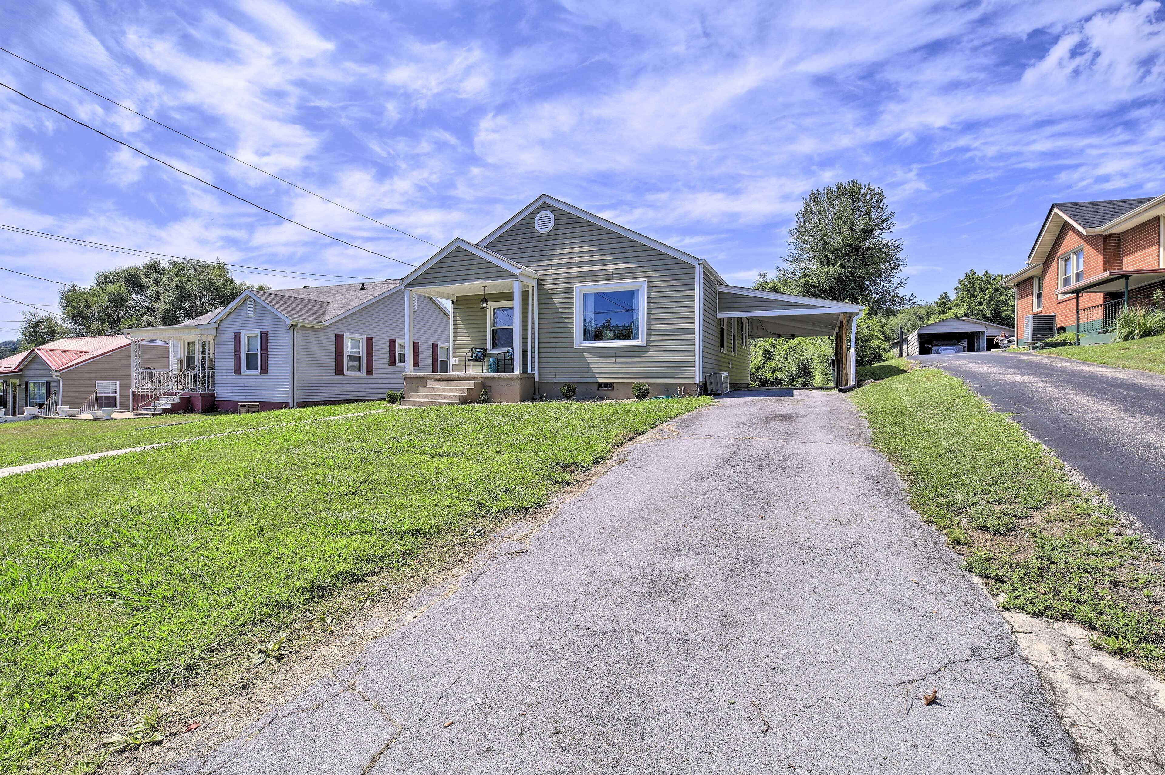 A single-story house with a front porch, a garage, and a driveway leading to the house.