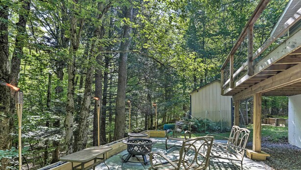 Un patio exterior con mobiliario de madera, una chimenea y una terraza de madera.