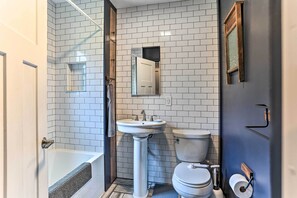 A bathroom with a white tiled wall, a pedestal sink, a toilet, and a bathtub. - Cozy White Lake Home w/ Patio, Deck & Grill! (White Lake)