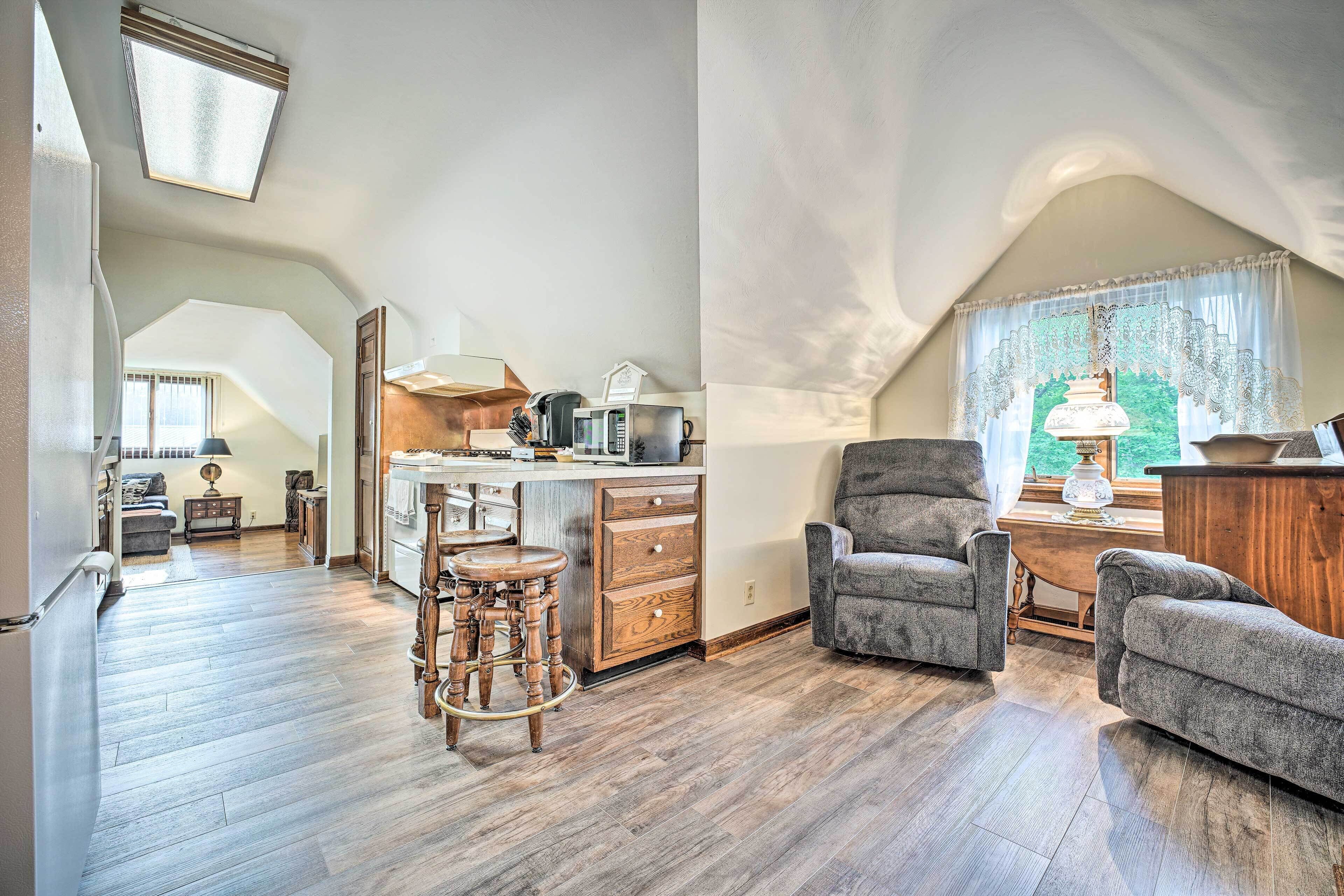 A spacious loft with a kitchen, dining area, and a cozy seating area with a high ceiling and skylight.