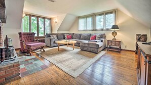 Ein geräumiges Wohnzimmer mit einer großen Couch, einem Kamin, Holzboden und großen Fenstern.