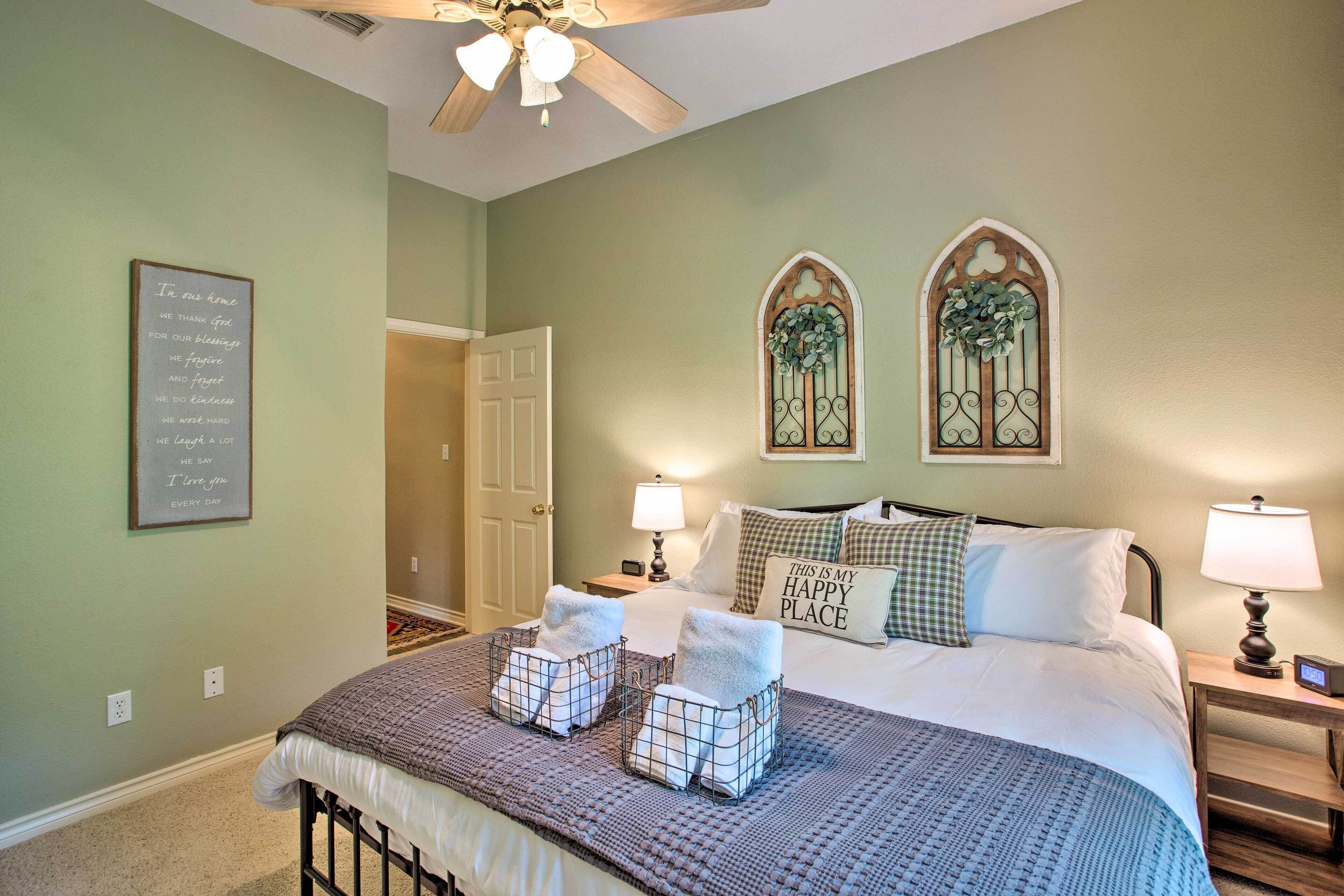 Ett välordnat sovrum med en säng, sänglampor, en väggklocka och en inramad, inspirerande citat.