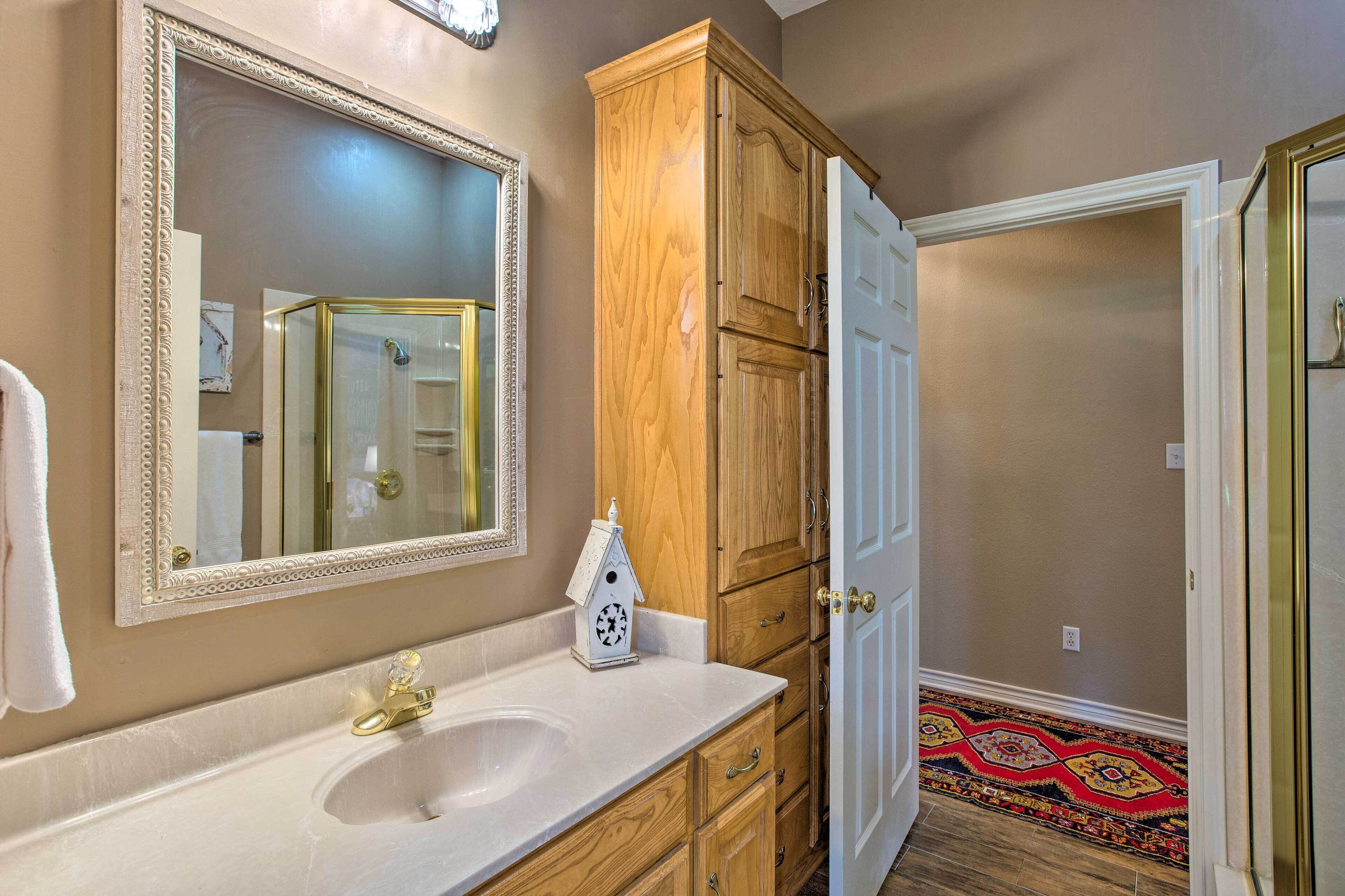 A bathroom with a white sink, a large mirror, wooden cabinets, and a patterned floor.