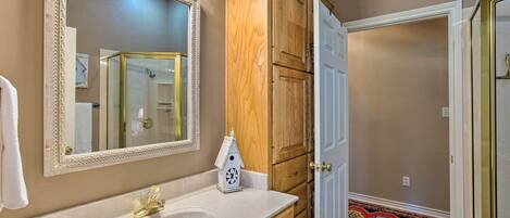 A bathroom with a white sink, a large mirror, wooden cabinets, and a patterned floor.