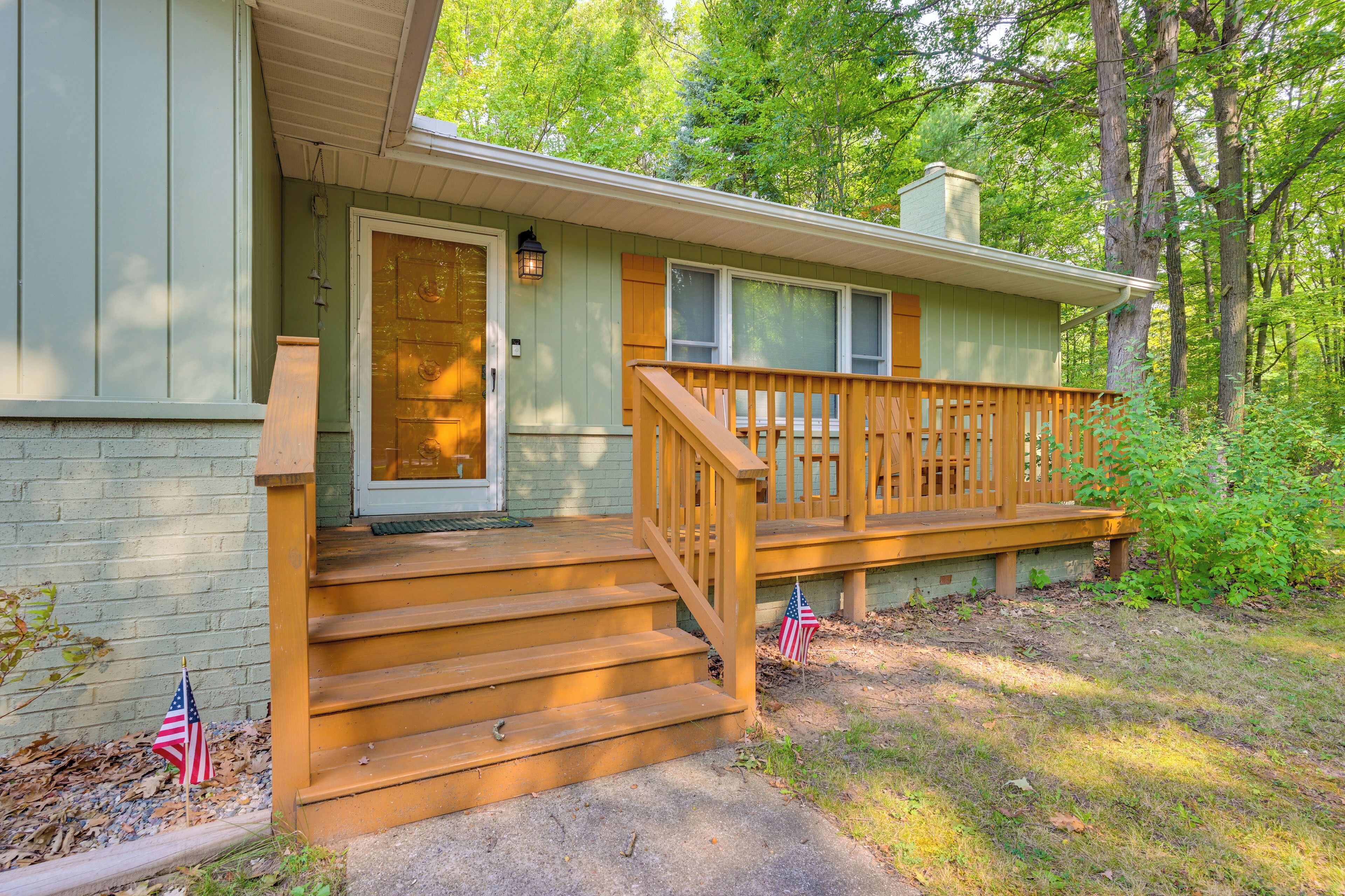 A house with a front porch, steps leading to the door, and an American flag on the ground.