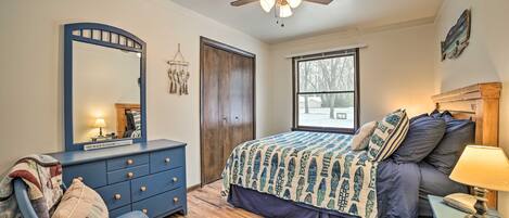 Une chambre à coucher comprenant un lit, une commode, une chaise et un ventilateur de plafond.